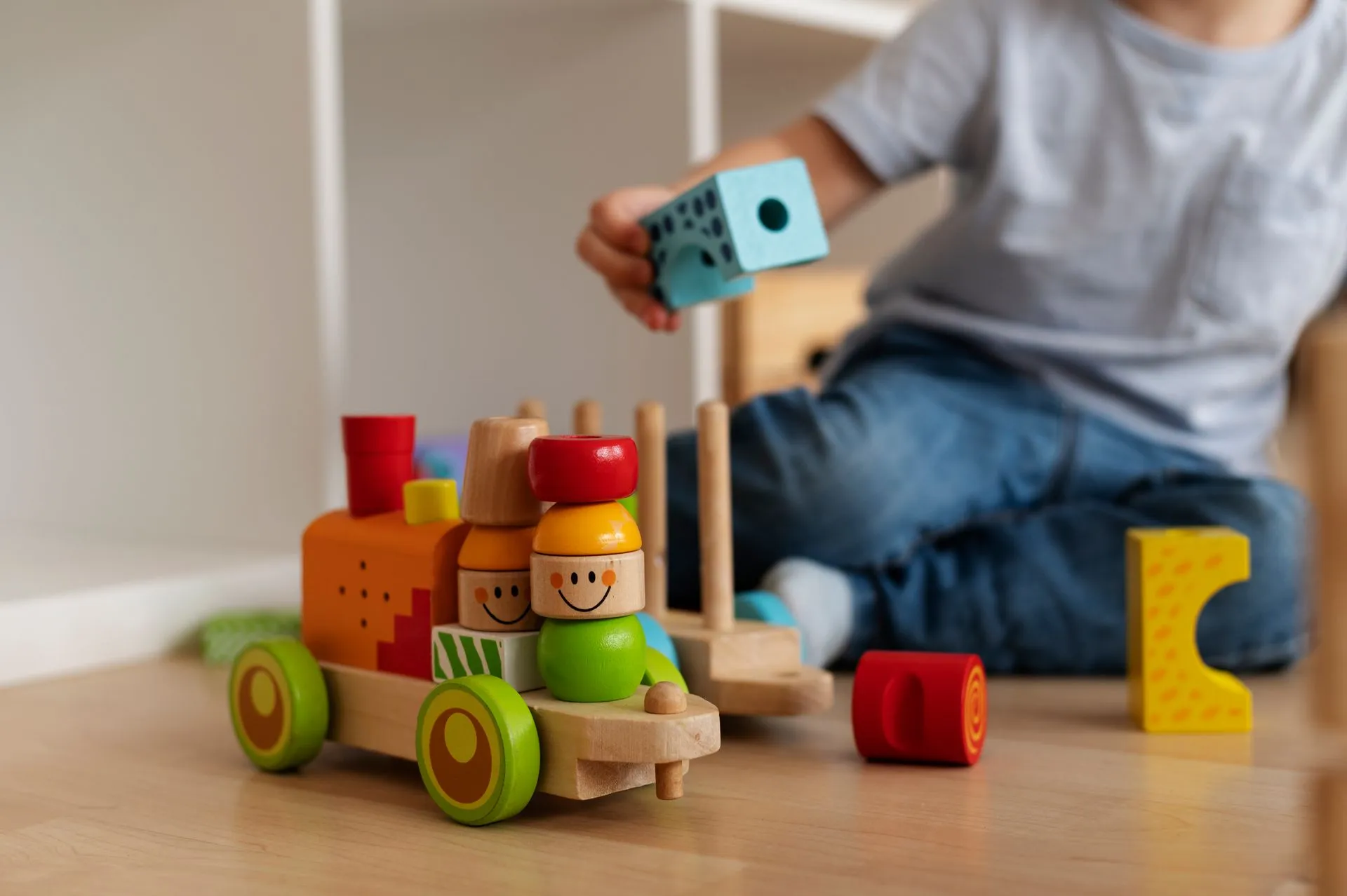 Child playing with a colorful wooden stacking train and blocks