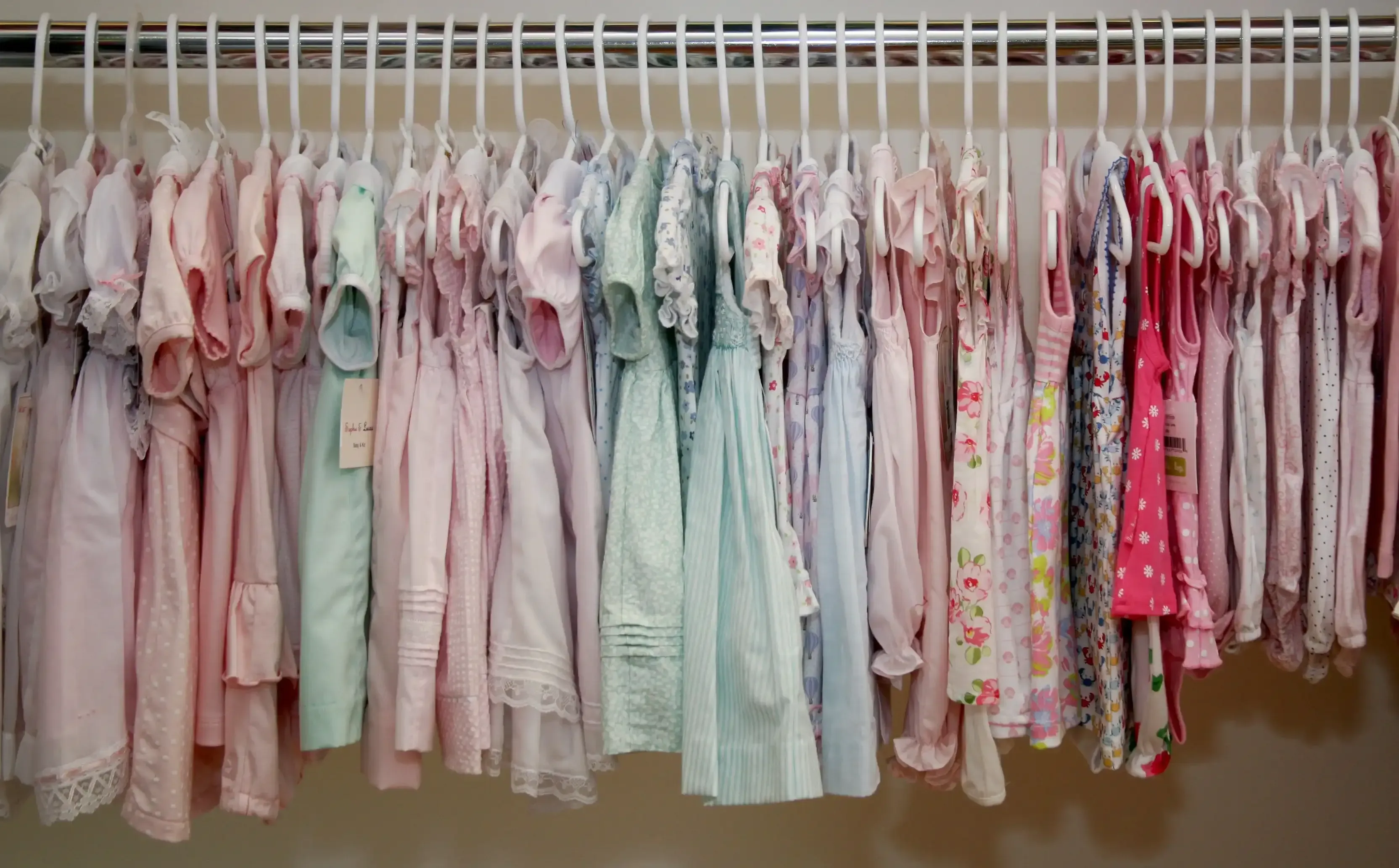 Rack of pastel smocked baby dresses and rompers at the boutique