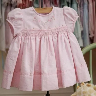 A pink dress is hanging on a wooden hanger