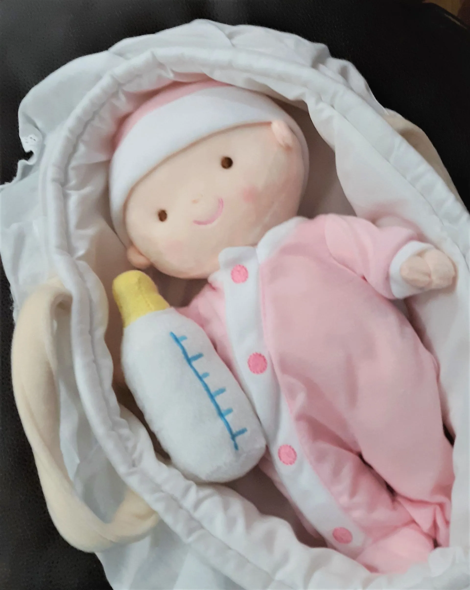 A stuffed baby doll with a bottle in a basket