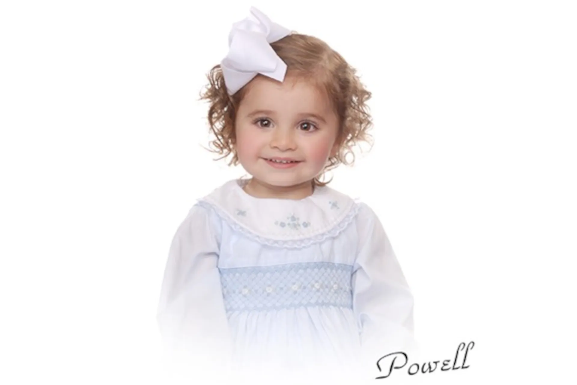 Toddler girl in a white dress with blue smocking and a big white hair bow